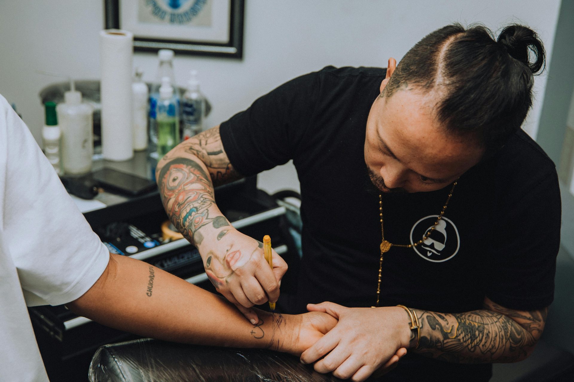 A skilled tattoo artist applies ink to a client's arm, crafting an intricate design in a studio setting.