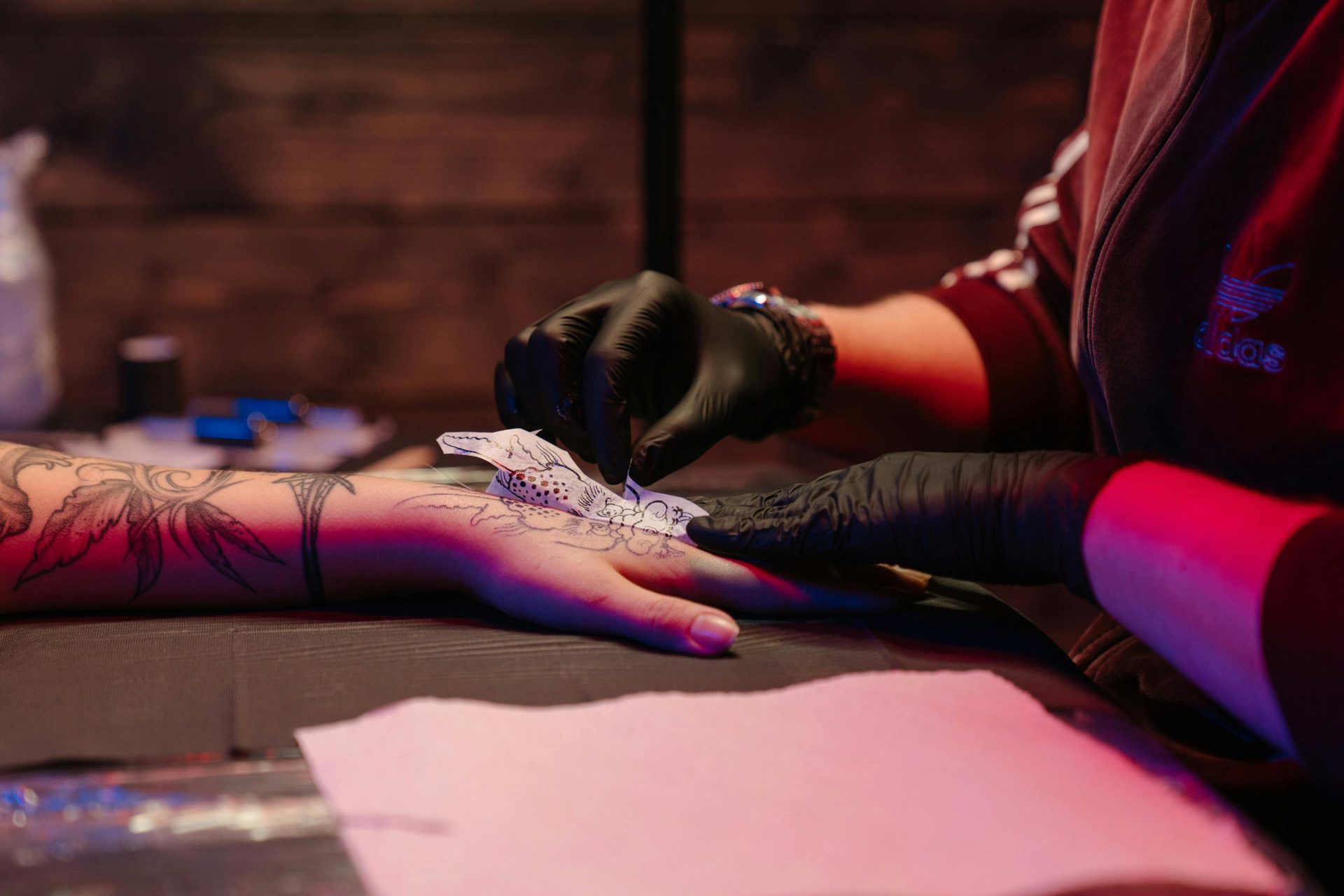 Tattoo artist in black gloves creating intricate design in studio, showcasing creativity and technique.