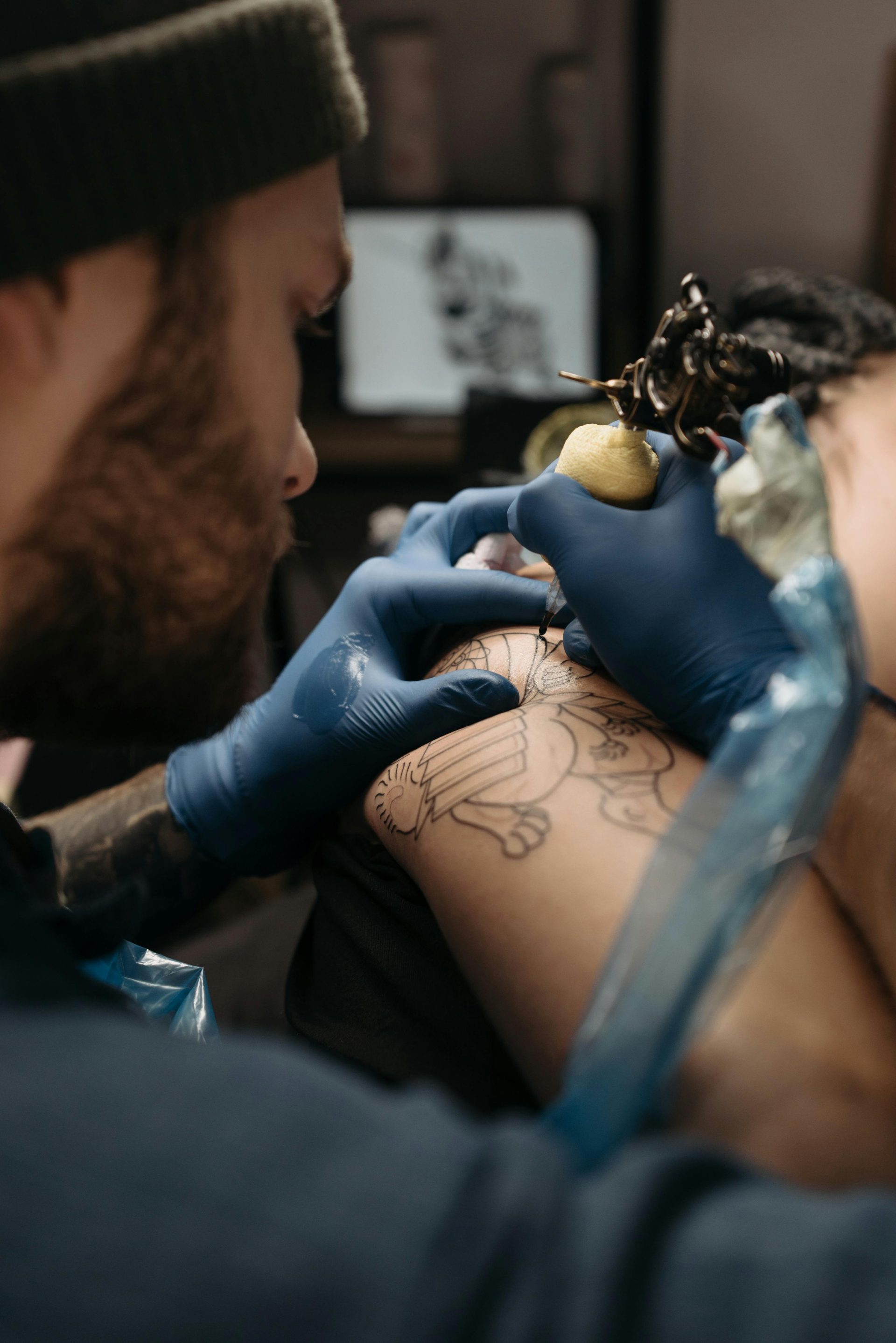 Close-up of a tattoo artist working on a client's arm using a tattoo machine.